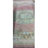 A large Chinese woollen Carpet, with decorative floral medallion centre on pink ground with