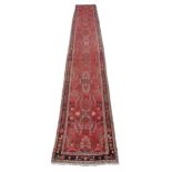 A semi-antique Middle Eastern woolen Carpet Runner, the burgundy ground multi-floral centre inside a