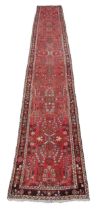 A semi-antique Middle Eastern woolen Carpet Runner, the burgundy ground multi-floral centre inside a