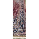 A large Middle Eastern burgundy ground woollen Carpet, the central panel with floral medallion