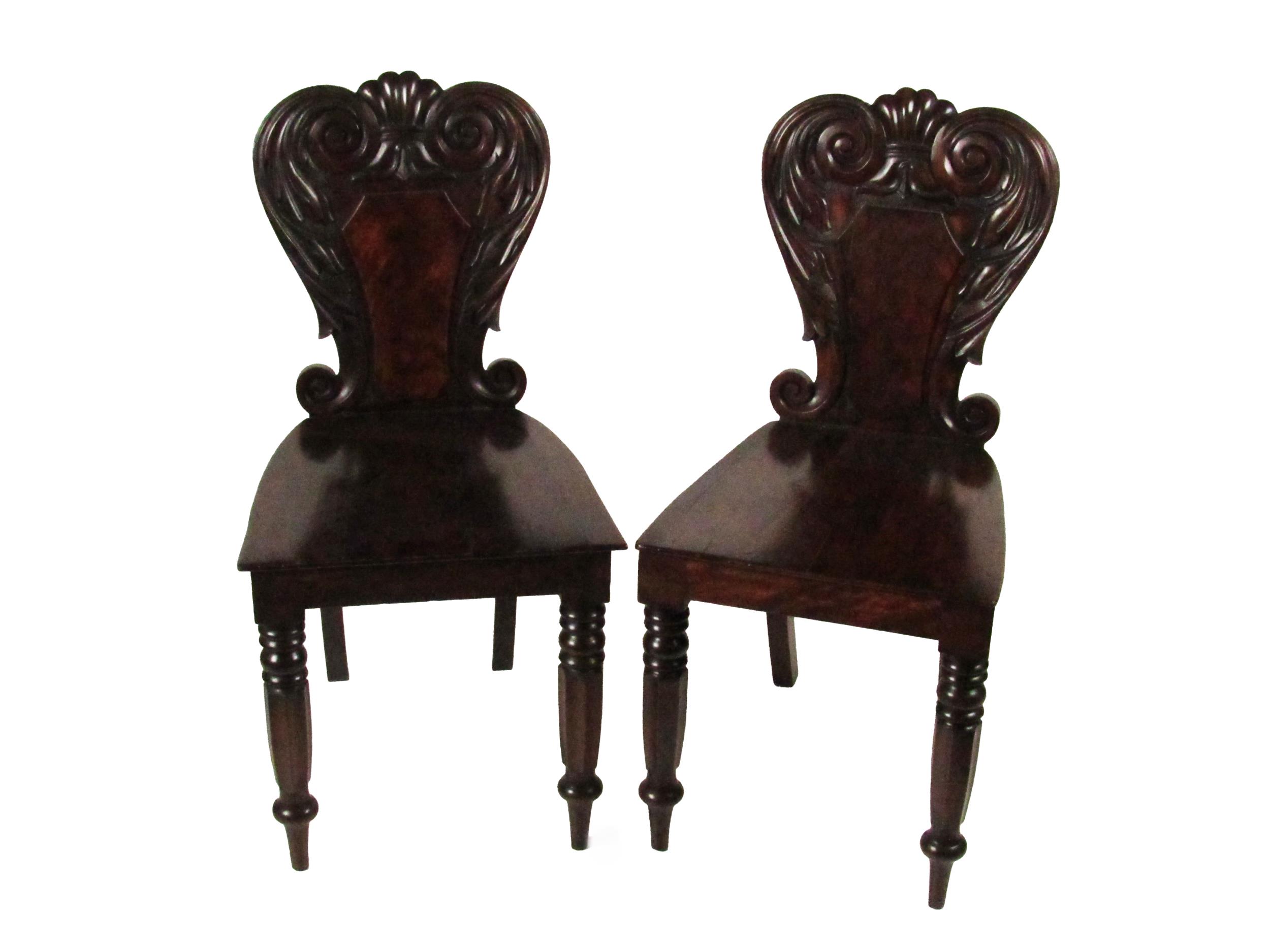 A pair of William IV Irish mahogany Hall Chairs, with carved shield backs over solid seats on