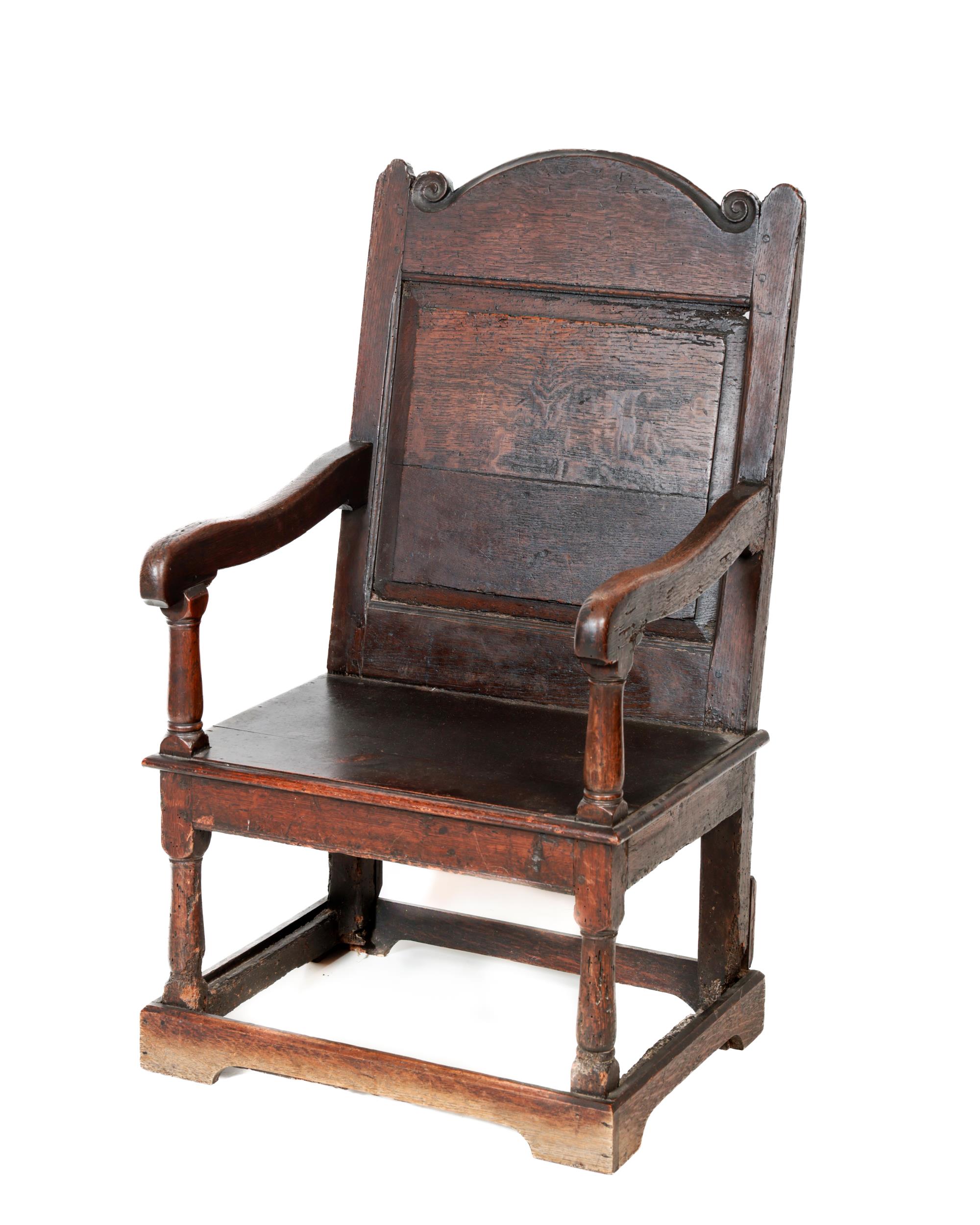 An 18th Century oak 'Wainscot' Armchair, the panelled back with turned capital, issuing shaped