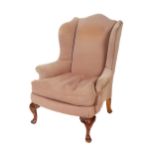 A 19th Century mahogany framed wing back Armchair, covered in cream fabric, with loose cushion, on