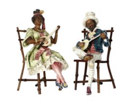 Pair of continental majolica glaze figures of musicians, a gentleman and lady modelled seated