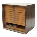 Twelve drawer wooden chest containing a quantity of watch parts including balances, stems, wheels,