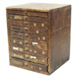 Nine drawer wooden chest containing a quantity of watch parts to include balance staffs, balances
