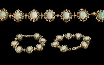 Ladies - attractive 9ct gold 7 stone opal set bracelet, all opals set in ornate open-worked setting.