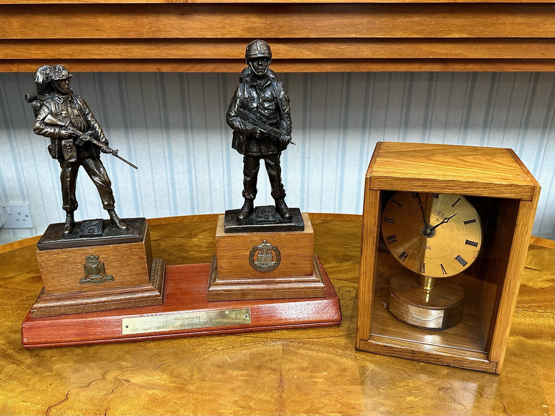 Military Interest A Presentation Clock housed in a wooden box. Together with a trophy of two armed