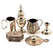 A silver sugar caster, candlestick, white metal tea strainer