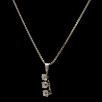 A diamond three stone pendant on chain.
