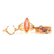 A carved shell cameo ring, a ruby and diamond triple shank ring, and an opal ring.