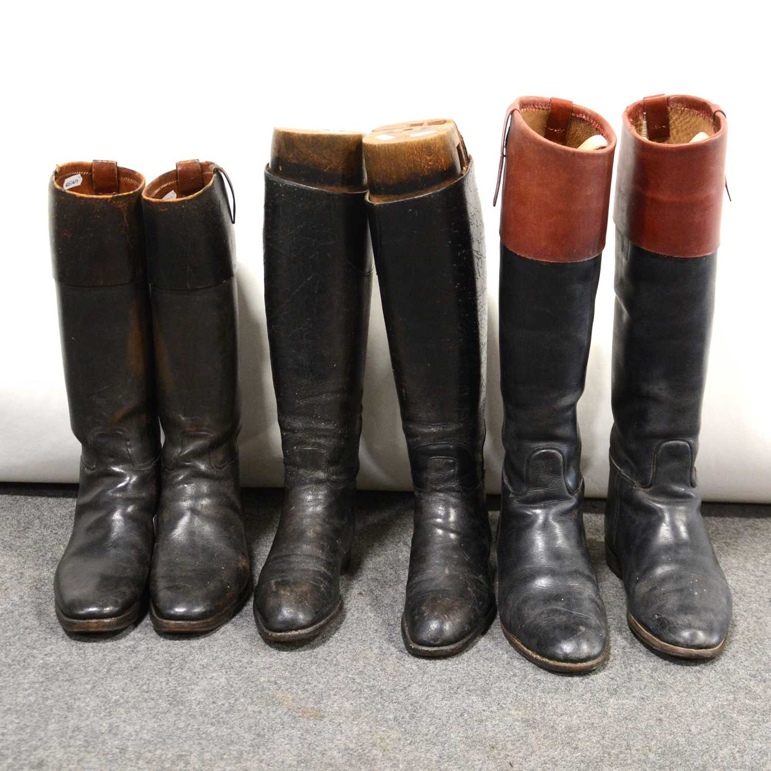 Three pairs of hunting boots, wooden trees and a hunting crop.