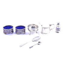 Silver condiments set, drum mustard, spoons, and white metal bowl.