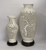 Two Chinese blanc de chine reticulated vase/lamps, on carved stands, largest 40cm high