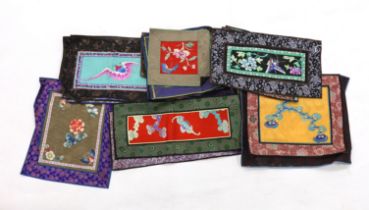 Twenty six assorted Chinese polychrome silk embroidered mats with silk damask borders of varying