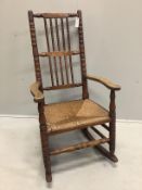 A late 19th century provincial fruitwood rush seat rocking chair, width 58cm, depth 46cm, height