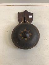 A circular Eastern bronze gong, diameter 32cm on oak shield shape back plate