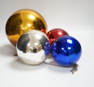 A gold witch’s ball and three small witch’s balls (silver, red and blue)