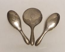 A pair of silver mounted hair brushes and a silver mounted hand mirror.