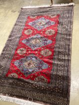 A Pakistan red ground triple medallion rug 200cm x 126cm.