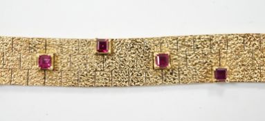 A textured yellow metal and eleven stone square cut ruby set bracelet, 16.5cm, gross weight 36.8