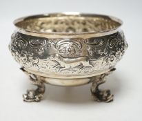 An Edwardian embossed silver bowl, on three dolphin supports, Wakely & Wheeler, London, 1905,