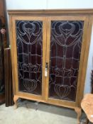 A pair of Art Nouveau stained glass panels, now as an oak bookcase, width 104cm, depth 29cm,