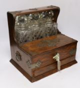 An oak tantalus/compendium containing three cut glass decanters, chess and draught sets, etc.
