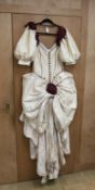 A late 20th century cream silk and burgundy trimmed gown, with bustle, possibly operatic or