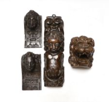Three 17th century carved oak figural corbels together with corbel end in the form of a lion,