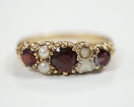 A modern 9ct gold, three stone garnet and four stone split pearl set half hoop ring (two pearls