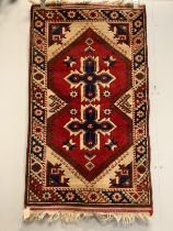 A Caucasian style red ground rug together with a North West Persian blue ground rug, larger 124 x