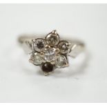 An 18ct white metal and seven stone diamond cluster set flower head ring (one stone missing), size