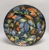 A large studio pottery plate by Sophie McCarthy, decorated with a variety of autumnal leaves, signed