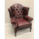 A Victorian style buttoned burgundy leather wing armchair
