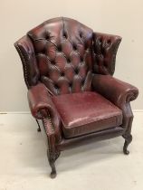 A Victorian style buttoned burgundy leather wing armchair