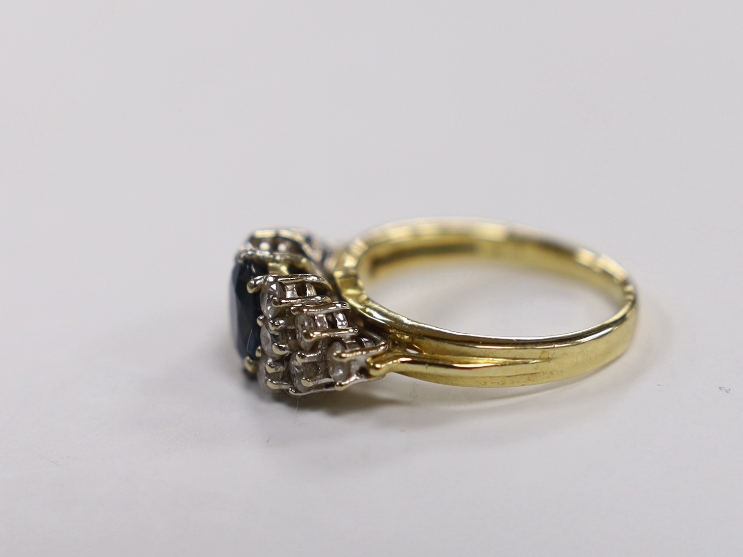 A modern 18ct gold and single stone oval cut sapphire set dress ring, with twelve stone diamond - Image 2 of 3