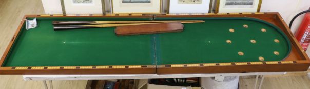 A Victorian folding cased bagatelle board, green baize interior with markers and two cues, 223.5cm