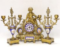 A 19th century ornate French gilt brass and porcelain clock, with two matching two branch candelabra