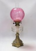 A Victorian brass based oil lamp, with cranberry glass shade,58cm high