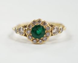 A Victorian style yellow metal emerald and diamond set circular cluster ring, with graduated diamond