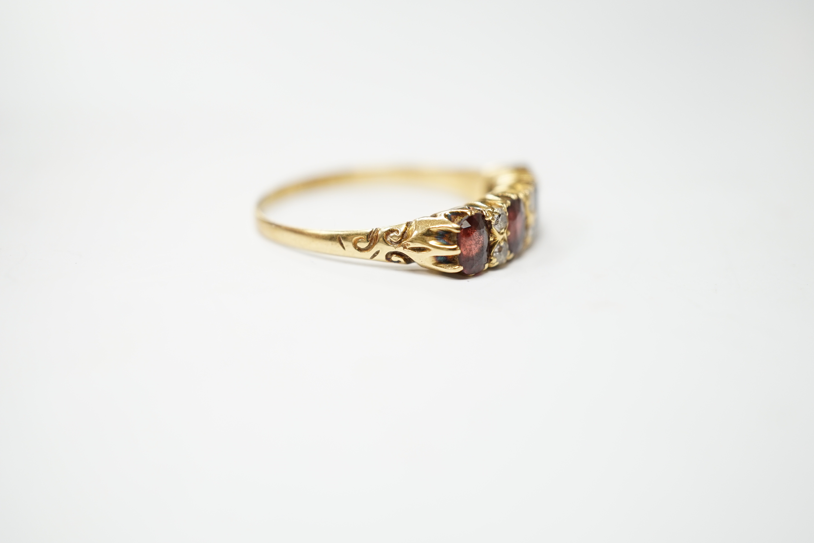 An Edwardian 18ct gold and four stone garnet set half hoop ring, with diamond chip spacers, size - Image 2 of 4
