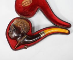 A cased Meerschaum pipe with a bowl modelled as a Nubian man’s head with metal mount and amber