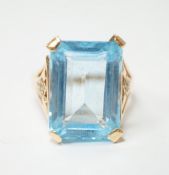 A yellow metal and single stone emerald cut blue topaz set dress ring, with ten stone diamond chip