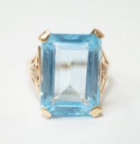 A yellow metal and single stone emerald cut blue topaz set dress ring, with ten stone diamond chip