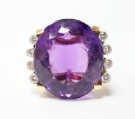 A large yellow and white metal and single stone oval cut amethyst set dress ring, flanked by eight