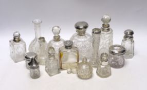 Fourteen assorted silver topped scent or toilet bottles and one without a mount, largest 14.7cm.