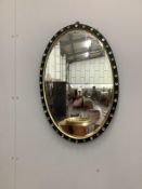 An oval ebonised Irish style wall mirror with glass boss border, width 50cm, height 74cm