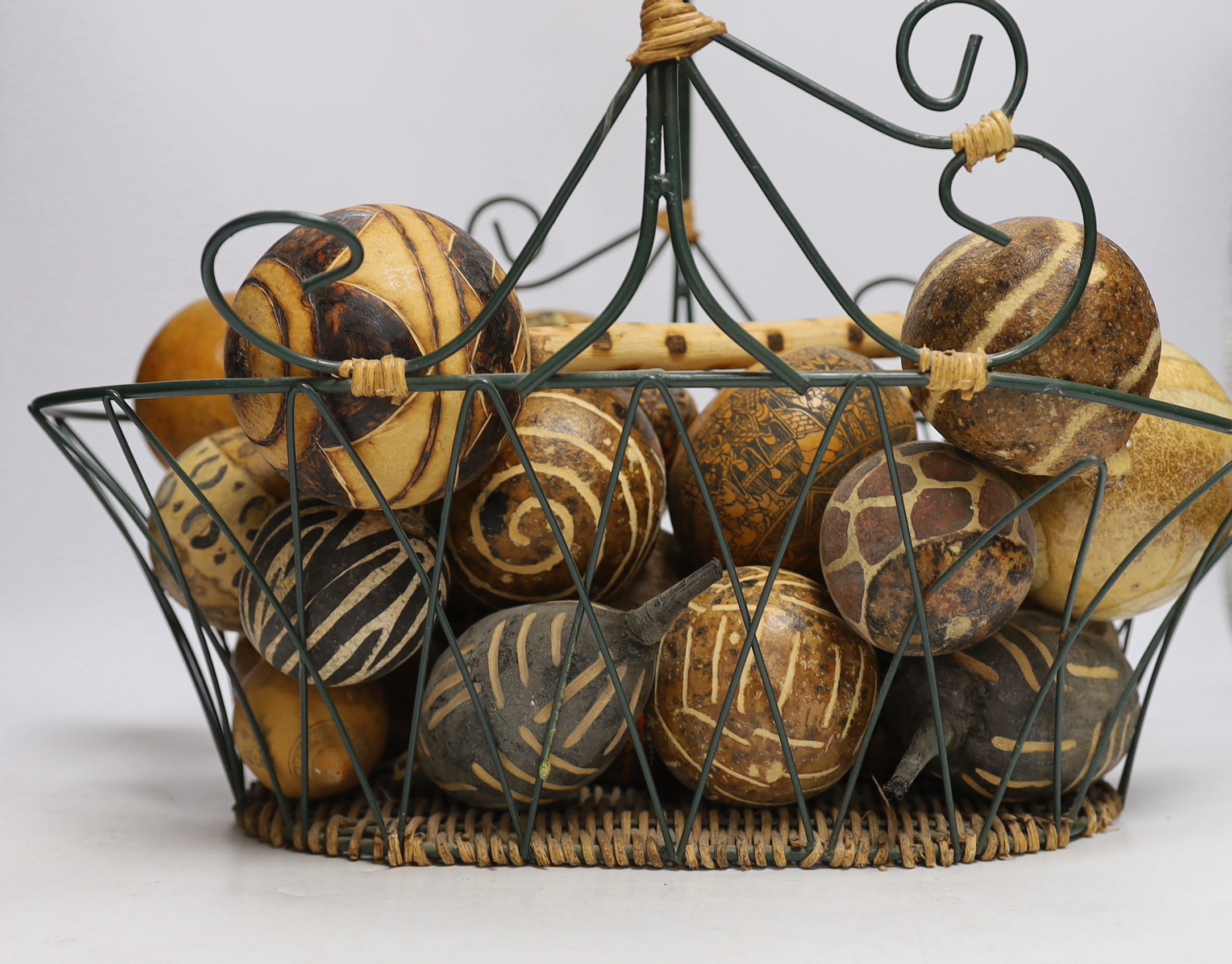 A wirework basket, containing assorted decorated gourds, nuts from Indonesia etc. - Image 2 of 3