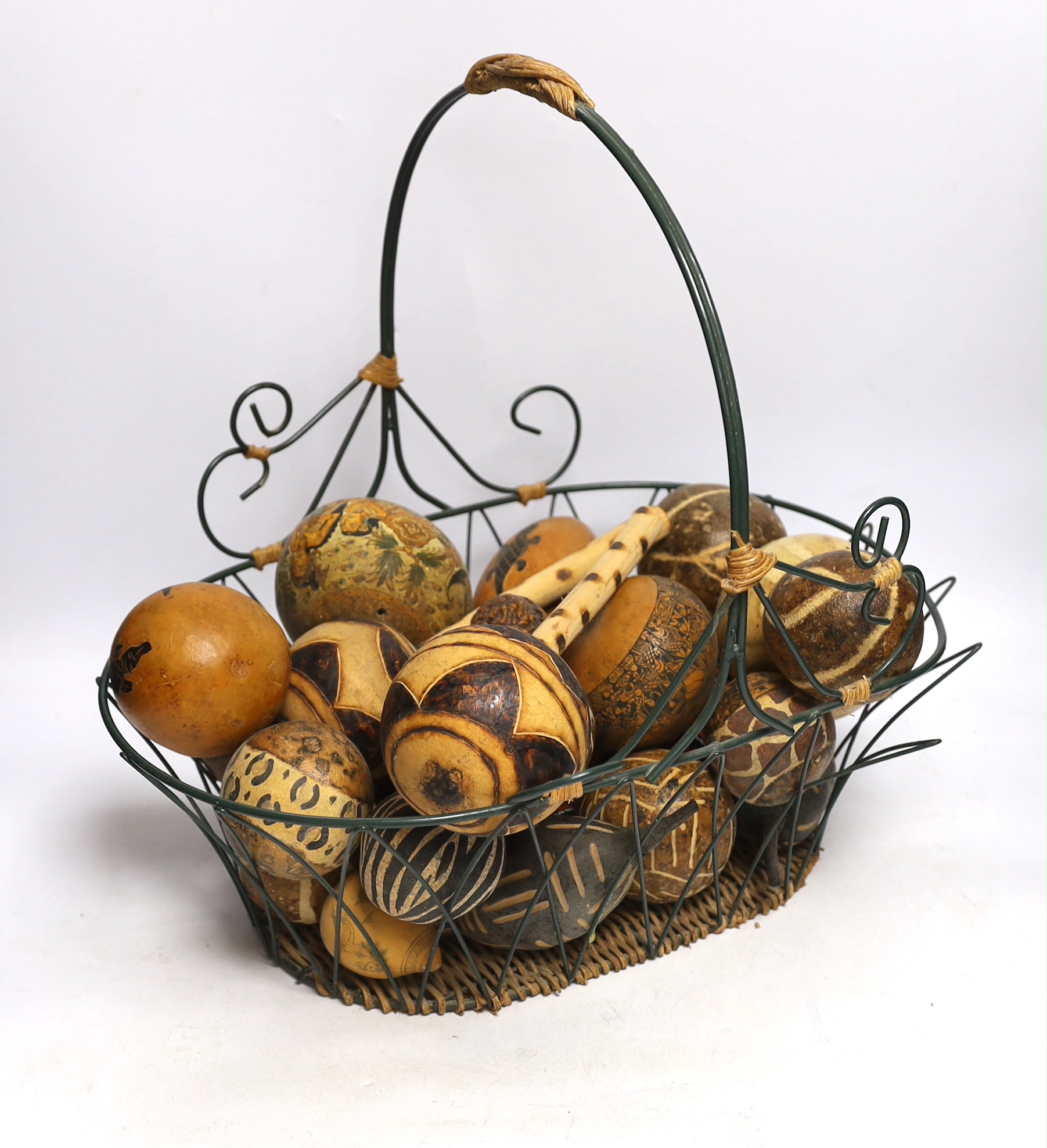 A wirework basket, containing assorted decorated gourds, nuts from Indonesia etc.